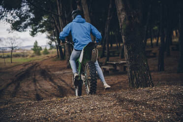 Männlicher jugendlicher Motorradfahrer auf einem Geländemotorrad im Wald - ACPF00902