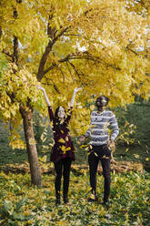 Glückliches multiethnisches Paar beim Spielen im Park im Herbst - EBBF01682