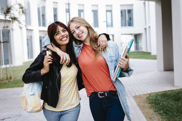 Glückliche junge Freunde, die sich auf dem Universitätscampus in den Armen liegen - TCEF01362