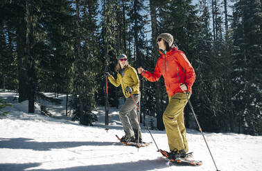 Zwei junge Frauen gehen an einem sonnigen Tag auf dem Mt. Hood Schneeschuhlaufen. - CAVF90843