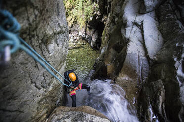 High angle view of man rappelling down waterfall in Cypress Canyon. - CAVF90862