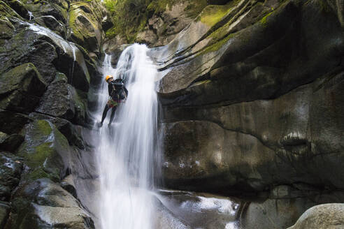 Rückansicht eines Mannes, der sich am Wasserfall im Cypress Creek Canyon abseilt. - CAVF90864