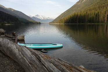 SUP-Board am Seeufer vor dem Hintergrund eines Bergkamms am Morgen - CAVF90874