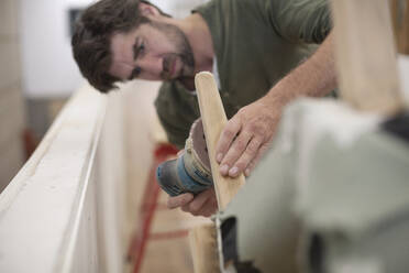 A focused man sands the leg of a chair - CAVF90907