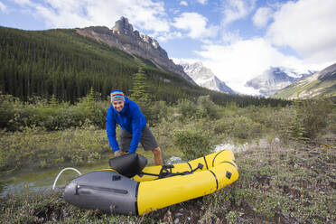 Excited man inflates his packraft before paddling the Alexandra River. - CAVF90927