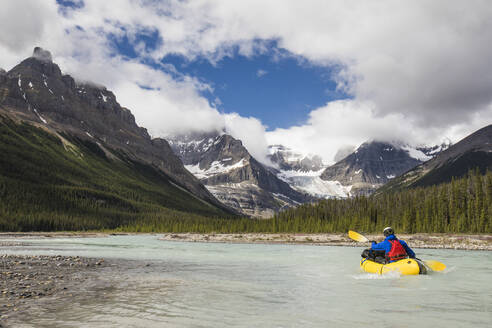 Forscher paddelt auf einem gelben Floß in Richtung der Rocky Mountains, Banff. - CAVF90931