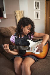 A little girl playing the electric guitar at home - CAVF90950