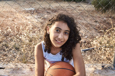 Close-up of a girl with curly hair with a metal fence background - CAVF90955