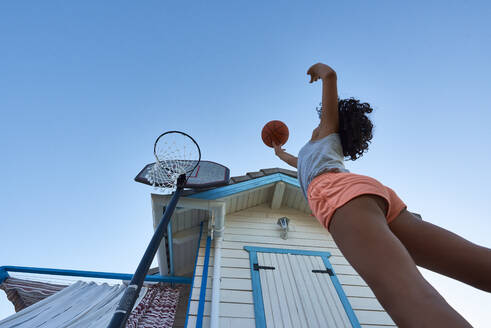 Ein Mädchen wirft einen Korb auf ihrem eigenen Basketballplatz von unten - CAVF90956