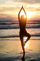 Silhouette of woman doing yoga at sunset - CAVF90966