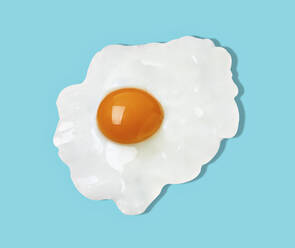 Fried egg against blue background - RAMF00101