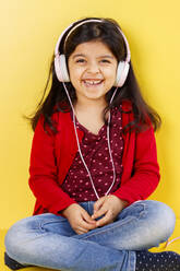 Niedliches kleines Mädchen, das mit ihren Kopfhörern Musik hört - CAVF90970