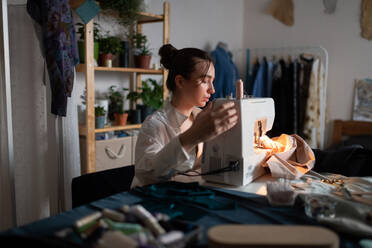 Female dressmaker using sewing machine at home - CAVF91004