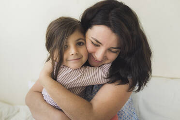 Smiling mid-30's mother hugging happy 6 yr old daughter - CAVF91065