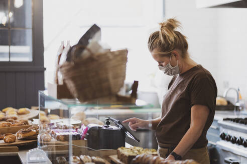 Waitress wearing face mask working in a cafe. - MINF15451