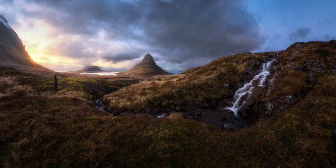 Erstaunlicher Panoramablick auf das grasbewachsene Hochland und den majestätischen Wasserfall bei Sonnenuntergang in Island - ADSF17744