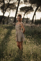 Peaceful female wearing summer dress standing on lawn in park in Iceland and tenderly looking at camera - ADSF17767