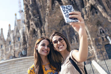 Freunde machen ein Selfie mit ihrem Mobiltelefon vor der Sagrada Familia in Barcelona, Katalonien, Spanien - JSRF01185