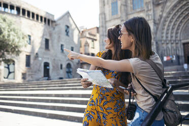 Friends studying map while standing at Barcelona Cathedral Square in Barcelona, Catalonia, Spain - JSRF01199