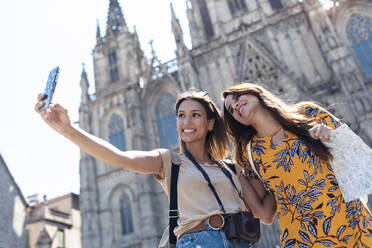 Freundinnen machen ein Selfie mit ihrem Handy auf dem Platz der Kathedrale von Barcelona in Barcelona, Katalonien, Spanien - JSRF01202