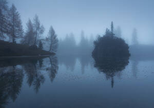 Scenic Blick auf Fluss mit felsigen Formation in der Nähe von Hügel mit wachsenden Bäumen im Nebel unter blauem Himmel im Winter - ADSF17898