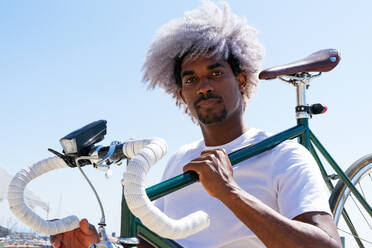 Afro and black man carrying a city bike on his back. Black rider and cyclist concept. Cycle through the city. - ADSF17987