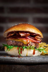Leckerer Hamburger mit Schnitzel und frischem Rucola, serviert auf dem Tisch im Café als nahrhaftes Mittagessen - ADSF18059