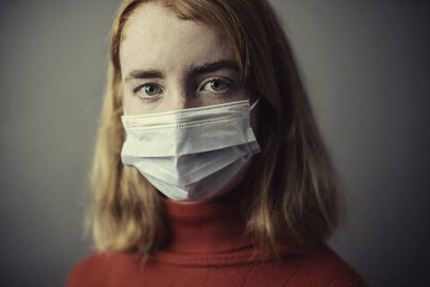 Teenage girl wearing protective face mask while standing against gray background stock photo