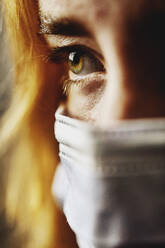 Close-up teenage girl eye wearing protective face mask on face - JATF01285