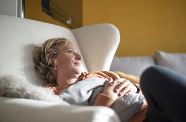 Woman looking away while relaxing on sofa at home - BFRF02310