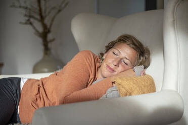 Mature woman napping while lying on sofa at home - BFRF02311