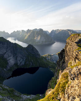 Wanderin bewundert die Aussicht, während sie auf einem Berg bei Reinebringen, Lofoten, Norwegen, steht - MALF00182