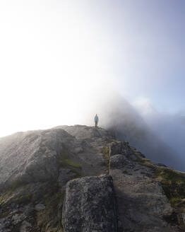 Frau steht auf einem Berg am Helvetestinden, Lofoten, Norwegen - MALF00202
