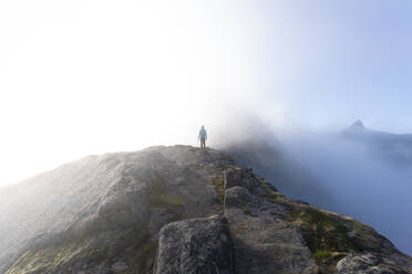 Hiker standing on mountain at Helvetestinden, Lofoten, Norway - MALF00203