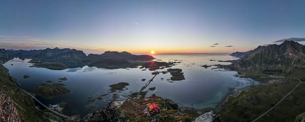 Wanderer bewundern die Aussicht, während sie auf einem Berg am Volandstinden, Lofoten, Norwegen, sitzen - MALF00238