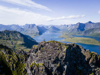 Female hiker standing on rocky mountain at Volandstinden, Lofoten, Norway - MALF00241