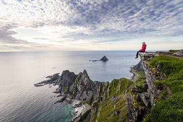 Explorer admiring view while sitting on Matind mountain at Andoya, Norway - MALF00279