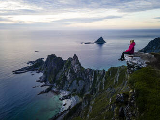 Frau sitzt und bewundert die Aussicht auf Matind, Andoya, Norwegen - MALF00282