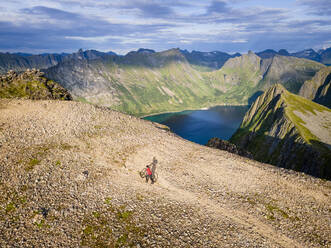 Männlicher Forscher mit Fahrrad auf einem Berg am Husfjellet, Senja, Norwegen - MALF00295