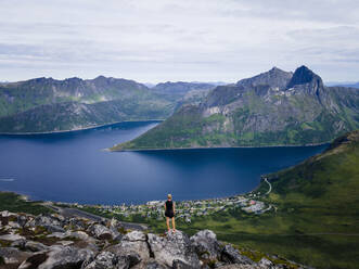Wanderer, der die Aussicht betrachtet, während er auf einem Berg in Segla, Norwegen, steht - MALF00307