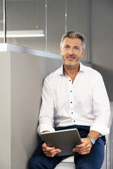 Unternehmerin mit digitalem Tablet im Büro sitzend - PESF02255