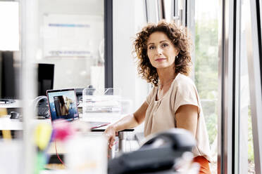 Selbstbewusste Geschäftsfrau sitzt am Schreibtisch im Büro - PESF02353