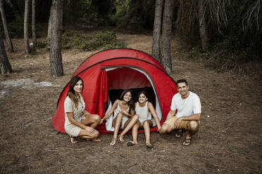Lächelnde Familie beim Zelten im Wald im Urlaub - RCPF00325