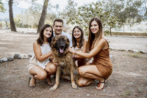 Smiling parents and children spending leisure time with dog in park during vacation stock photo