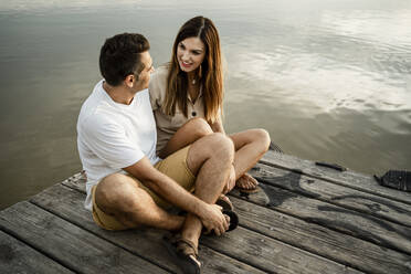 Couple sitting against lake at jetty - RCPF00349