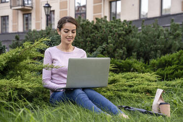 Young businesswoman using laptop while sitting in park - VPIF03272