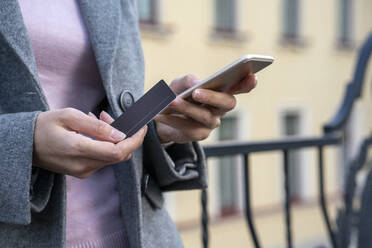 Businesswoman holding credit card while making payment through mobile phone - VPIF03274