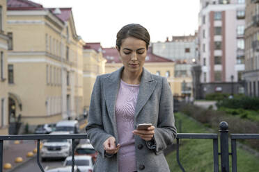 Unternehmerin mit Kreditkarte beim Bezahlen mit dem Smartphone in der Stadt - VPIF03275