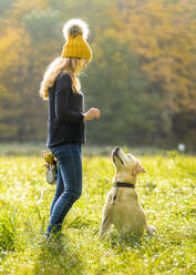 Junge Frau steht mit Labrador Retriever im Park - STSF02692