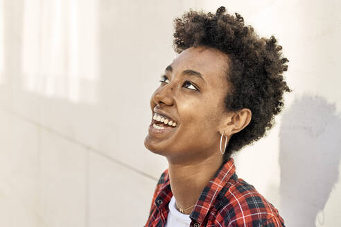Lächelnde junge Afro-Hipsterin, die gegen eine weiße Wand blickt - VEGF03189